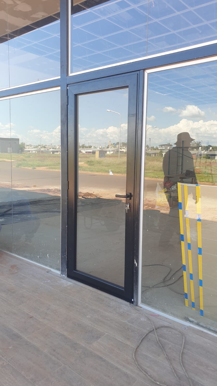 Puerta de aluminio negro y paños vidriados en obra