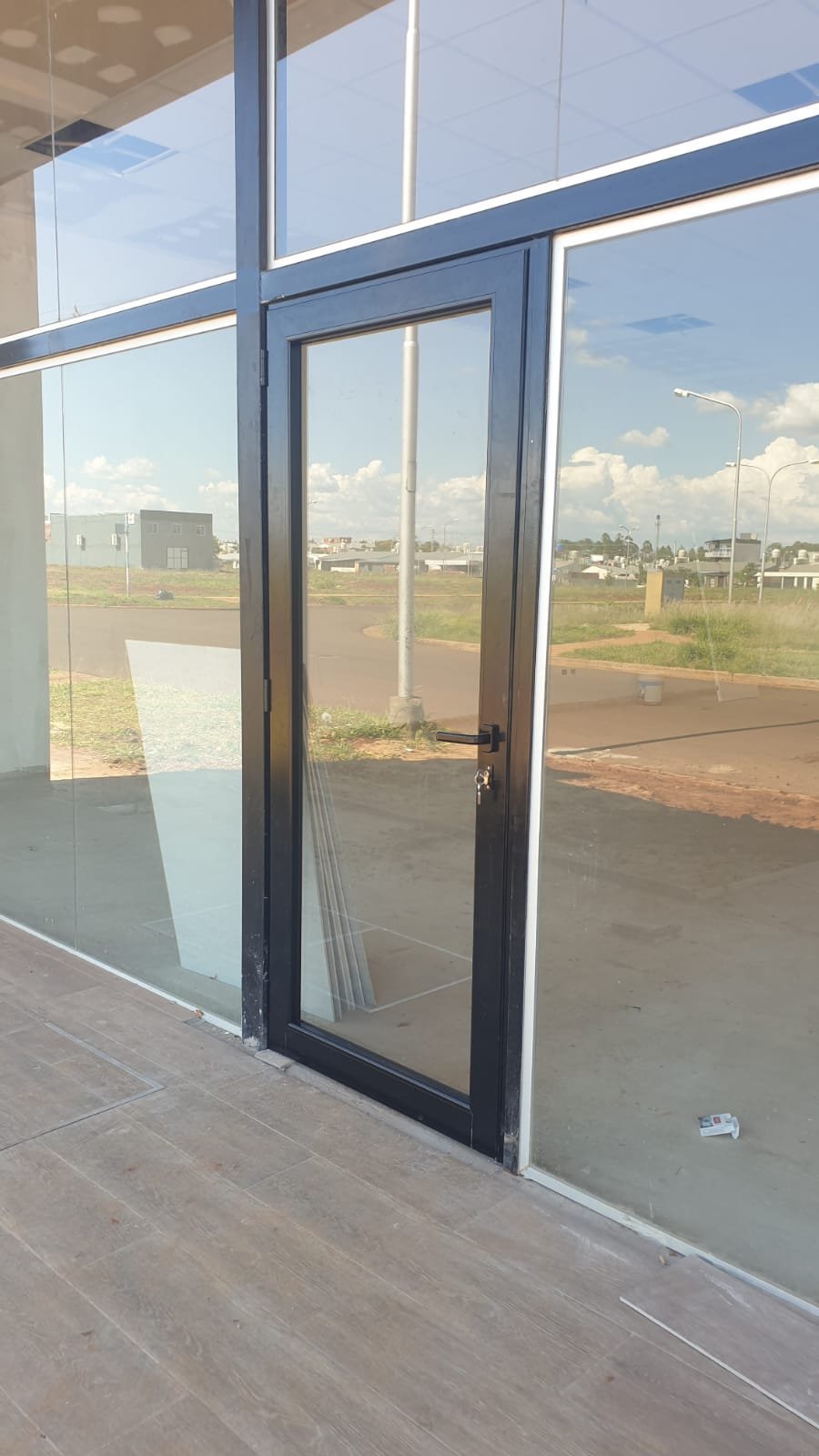 Puerta y paños vidriados de aluminio negro en obra terminada